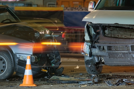 Damaged in heavy car accident vehicles after collision on city street crash site at night