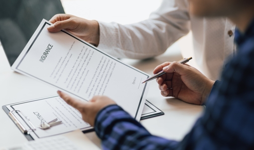 Man in office showing an insurance policy and pointing with a pen where the policyholder must to sign