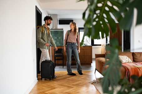 Young couple arriving at a cozy apartment with their luggage stock photo