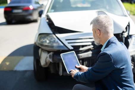 Accident investigator inspecting the damaged areas of a vehicle stock photo