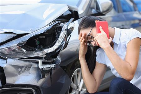 Sad woman talking on cell phone near wrecked car stock photo