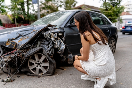 women looking at her damaged car after an accident