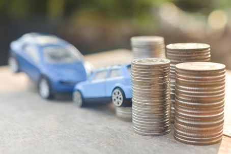 Coins stack and car model on wood table stock photo