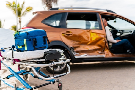 Emergency stretcher beside damaged car with senior man inside stock photo