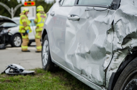 Close up on a car crashed with fireman in background
