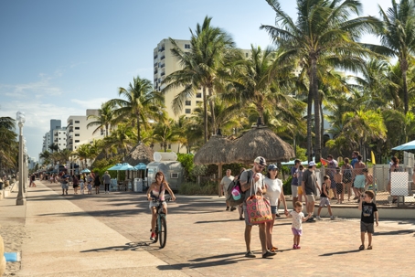 Fort Lauderdale people walk along the palm tree lined boardwalk on the beach stock photo