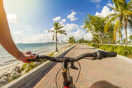 man riding a bicycle in front of a paradise blue sea landscape