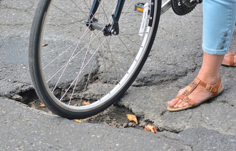 female cyclists rolling bike stuck in a pothole