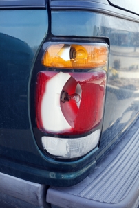 blue pick-up truck with a broken tail light