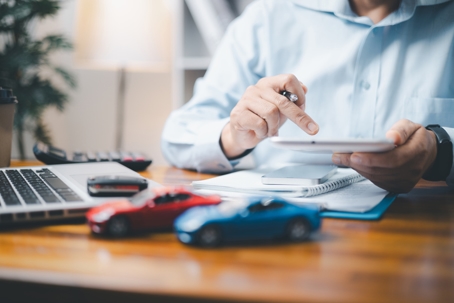 Toy Car In Front Of Businessman Calculating Loan.