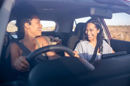 Woman friends in car laughing while driving stock photo