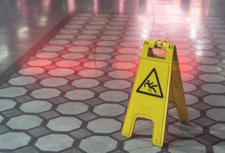 Yellow warning plate wit Caution wet floor icon on slippery tile floor stock photo