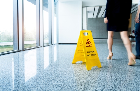 Caution wet floor sign with motion blurred legs walking stock photo