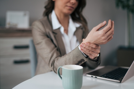 Shot of an unrecognisable businesswoman experiencing wrist pain while working in a modern office stock photo
