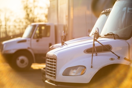 Middle rig semi Trucks standing at the gates of the warehouse for loading lit by the sun stock photo