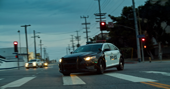 Cop Car Turning onto Downtown LA Street in the Evening stock photo