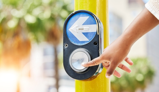 Crosswalk, arrow and button with hand of woman in city for traffic light, intersection