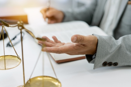 Freelance legal consultant advises client on a lawsuit, discussing plans and rights while focusing on honesty and integrity, with legal books and scales at hand in a professional setting. stock photo