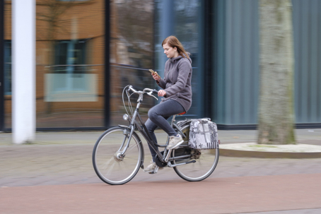 Girl riding a bike and looks at her smartphone, danger stock photo