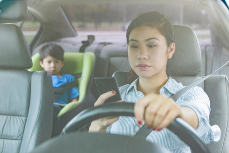 Mom texts while driving with child in the backseat stock photo