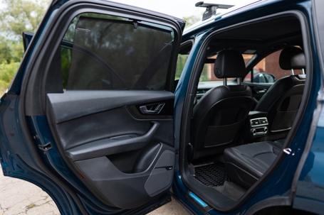 Rear passenger's door of luxury automobile being opened while vehicle being parked in urban area. Clear lines and stylish design of modern car stock photo