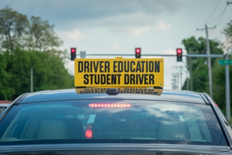 Student driver sign on top of car at stoplight stock photo