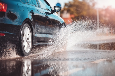 Car driving through the puddle and splashing by water