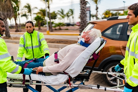 Paramedic helping senior victim on car accident stock photo