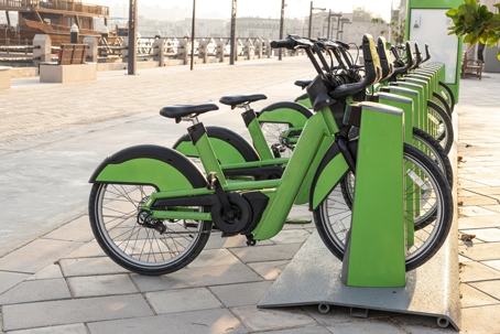 Electric bicycles for rent are green in parking lot in the city center on the street