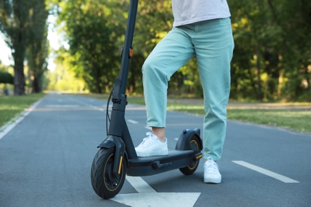 Woman with modern electric kick scooter in park