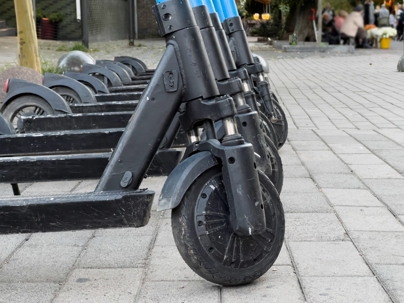 A row of electric scooters stands ready for riders along the busy city sidewalk, with pedestrians and vibrant surroundings adding to the lively atmosphere of the afternoon stock photo