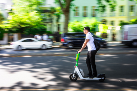 Blurred motion of man riding Lime E-scooter on road