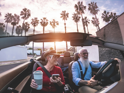 Senior trendy couple inside a convertible car on holiday time - Mature people having fun doing a road trip during vacation - Travel, fashion and joyful elderly concept - Main focus on woman face stock photo