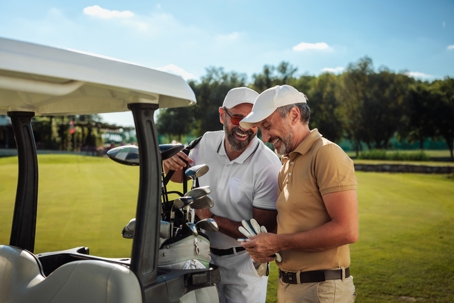 Two friends laughing by the golf cart on the field stock photo