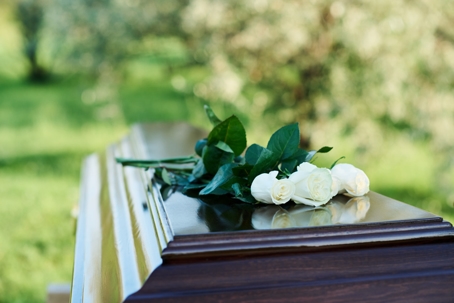 Focus on bunch of several fresh white roses on top of closed coffin lid