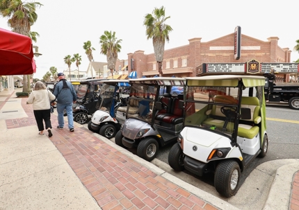 Couple walks pass golf carts. stock photo