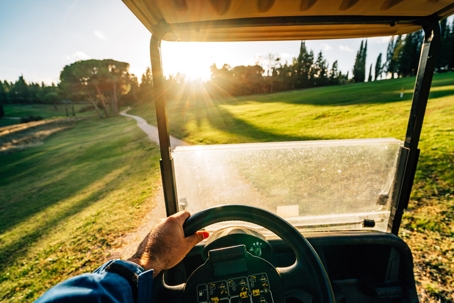 Pov view of a man driving a golf cart at sunset