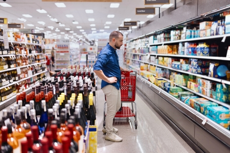 A man chooses a selection of beverages from the drinks aisle stock photo