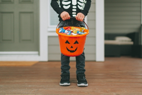 little boy in a skeleton costume holding a trick or treat basket