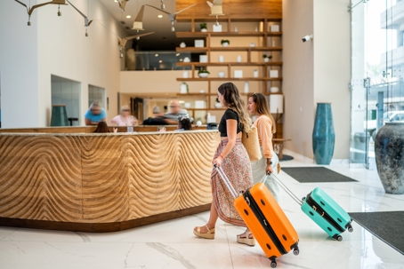 Traveler friends arriving at a hotel with their luggage stock photo