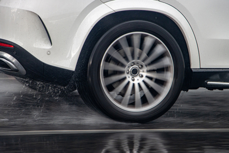 Detail of the rear wheel of a car driving in the rain on a wet road. stock photo