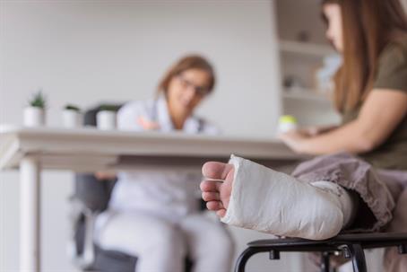 Teenager with broken leg receiving medical support from doctor stock photo