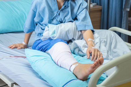 woman patient lying with bandage compression knee brace support injury on the bed in nursing ward hospital
