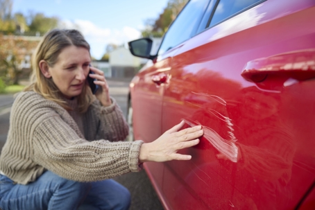 Unhappy Mature Female Driver With Damaged Car After Accident Calling Insurance Company On Mobile Phone stock photo