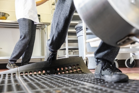 A man trips in a commercial kitchen. stock photo