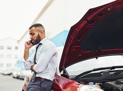 man on the phone next to a damaged car
