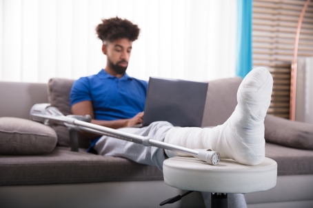 Man With Broken Leg Using Laptop stock photo