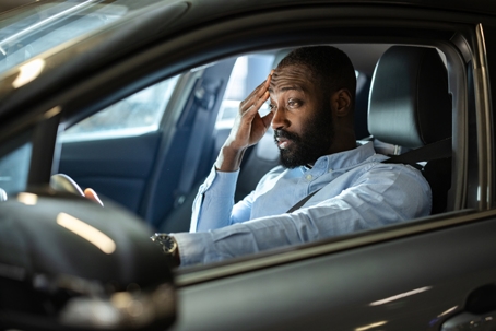 Man feeling overwhelmed while sitting in a parked car at night stock photo
