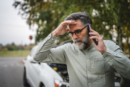 Worried man stand in front open hood of car make a phone call for help stock photo