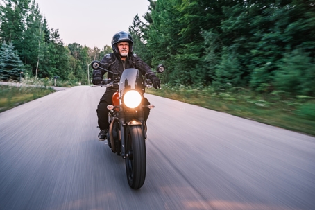 Mature man riding his motorbike in the countryside at dawn stock photo